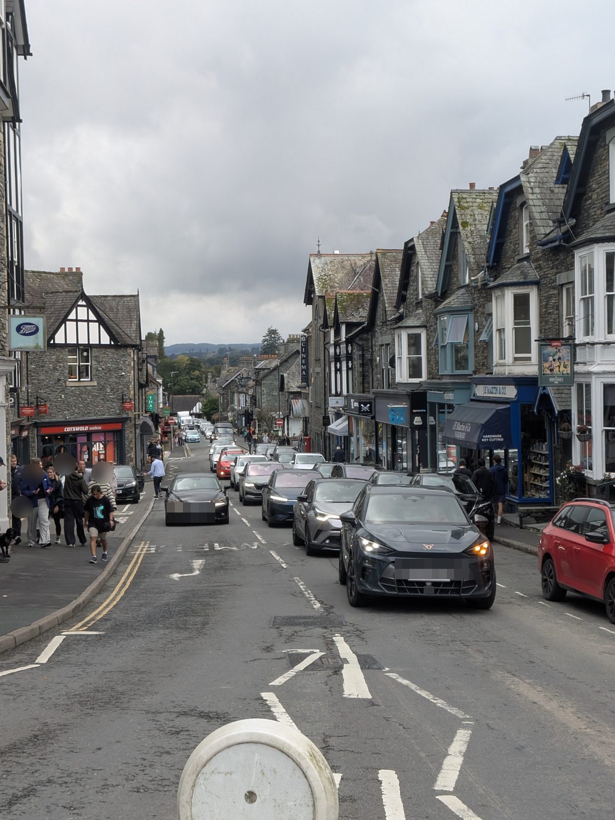 The main road through Ambleside, lined with slate shopfronts, traffic queued in both directions