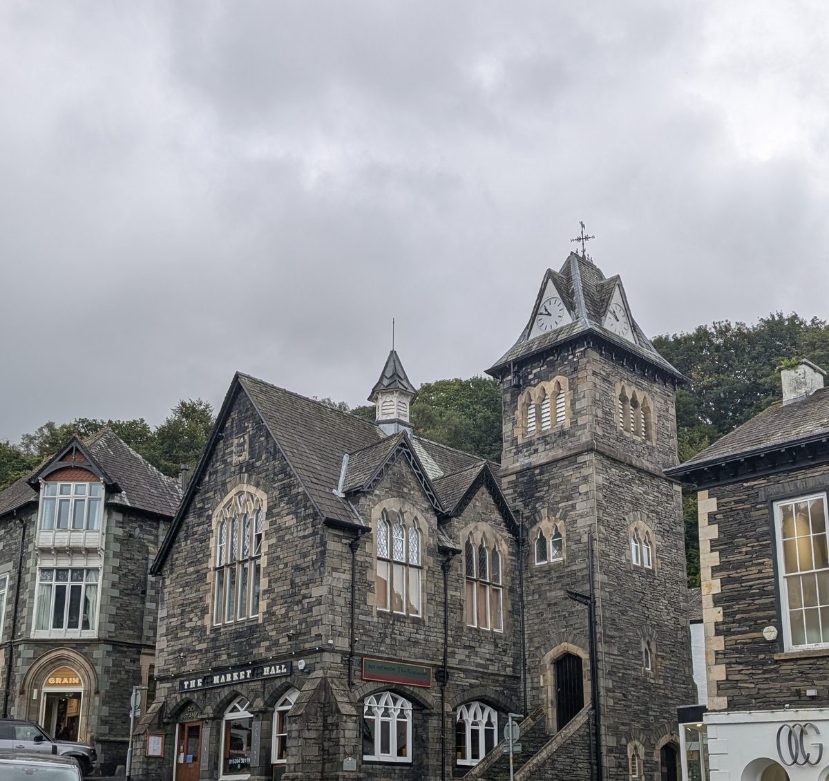 The Market Hall in Ambleside: a gabled stone building with pointed windows and a clock tower, under a grey sky