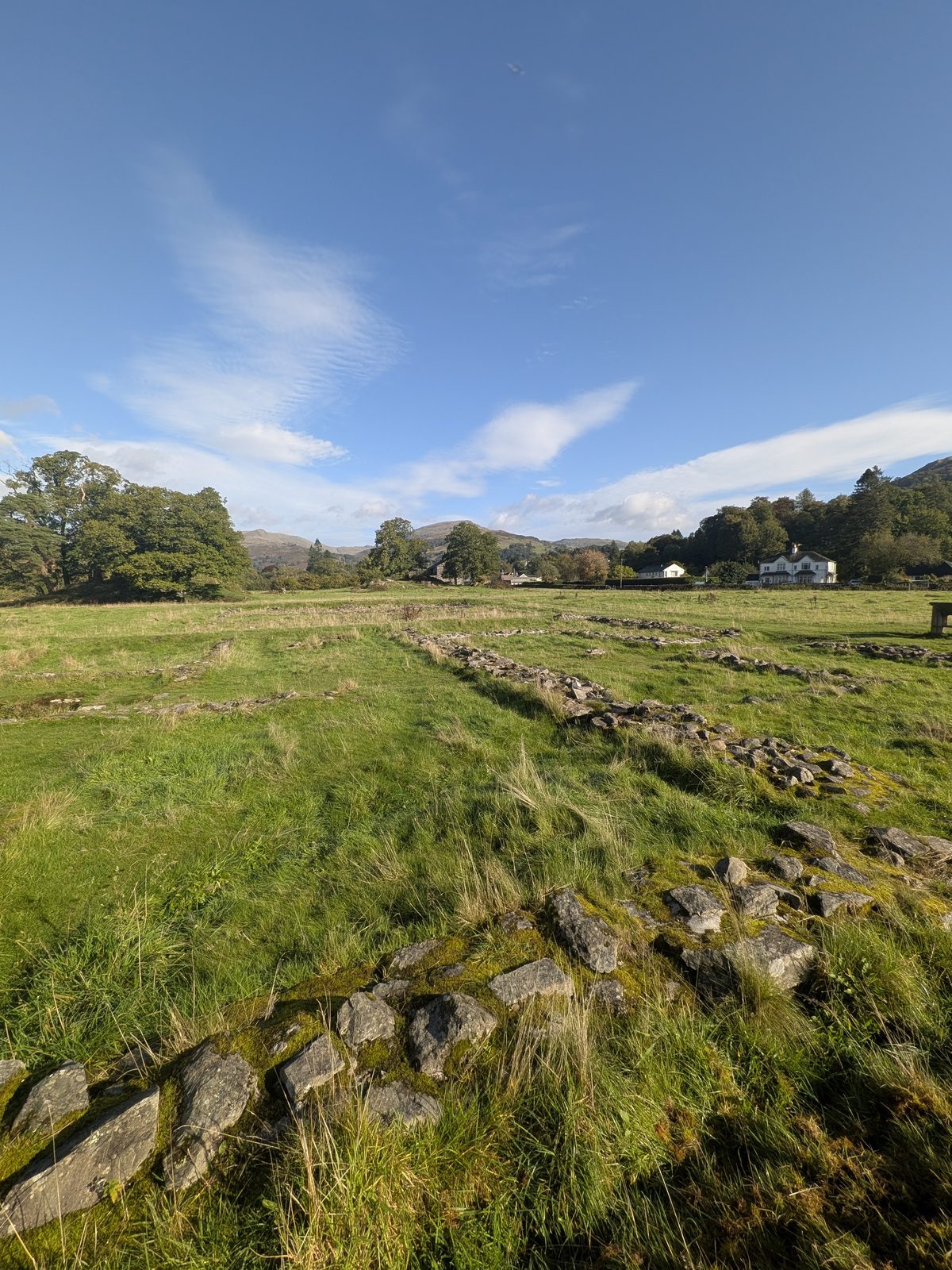 A line of Roman wall footings running through the grass at Ambleside Roman Fort