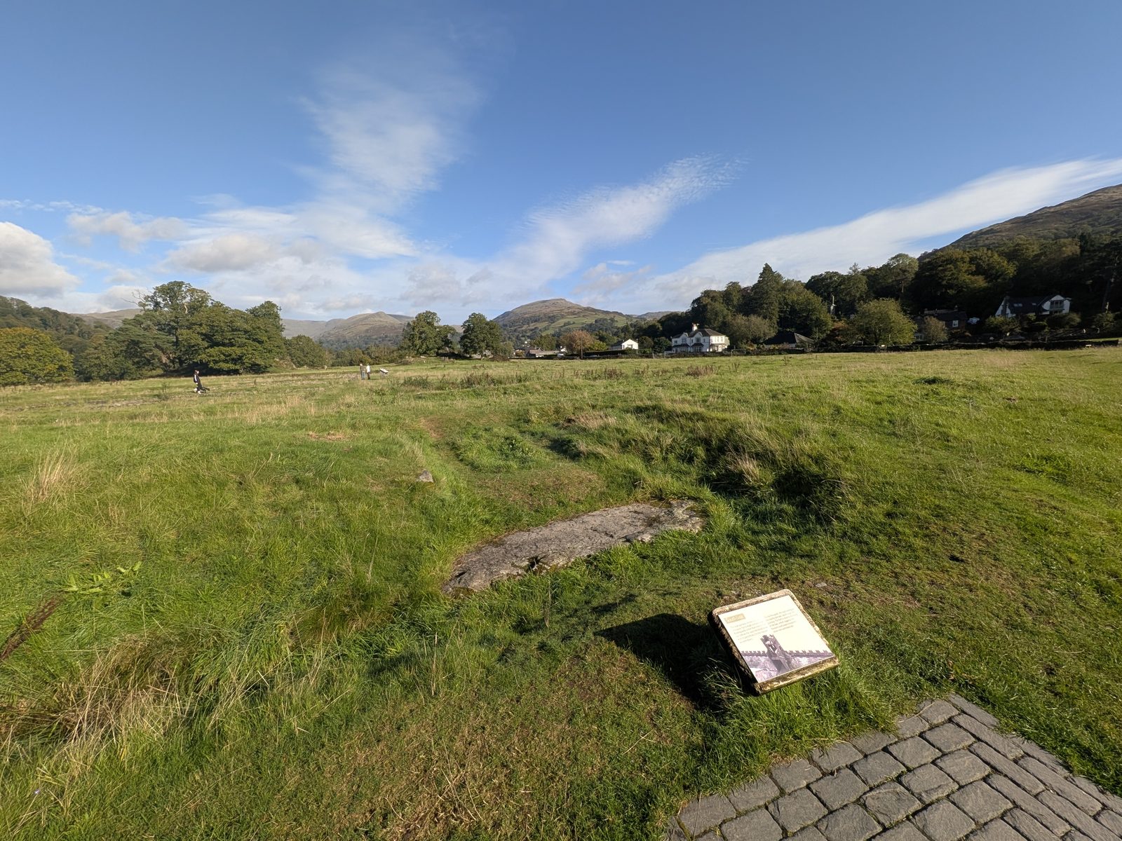 The south gate of Ambleside Roman Fort: paving, a plaque and a stone set in the turf