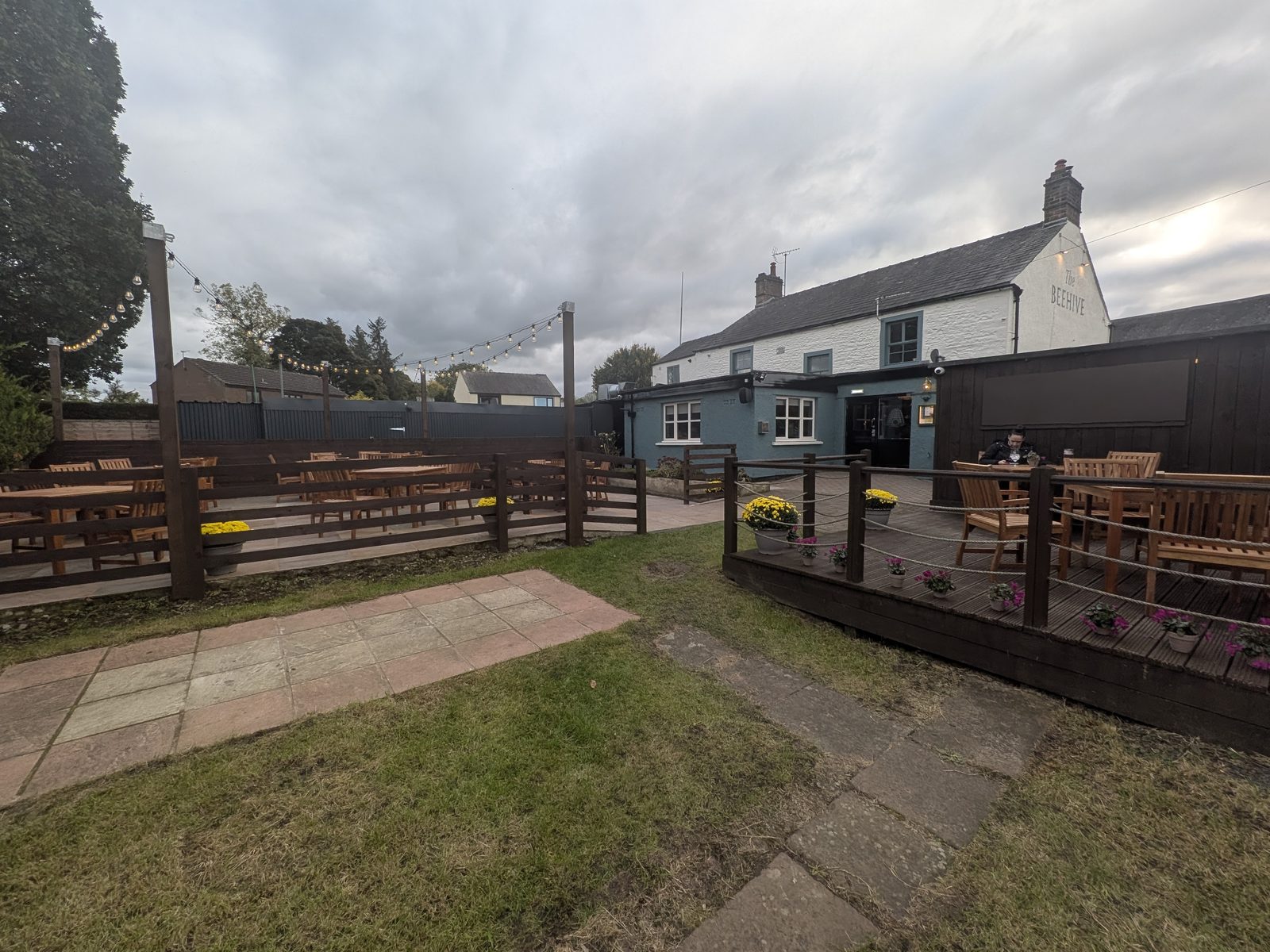 The decking and garden tables at The Beehive, Eamont Bridge, with the white pub building behind