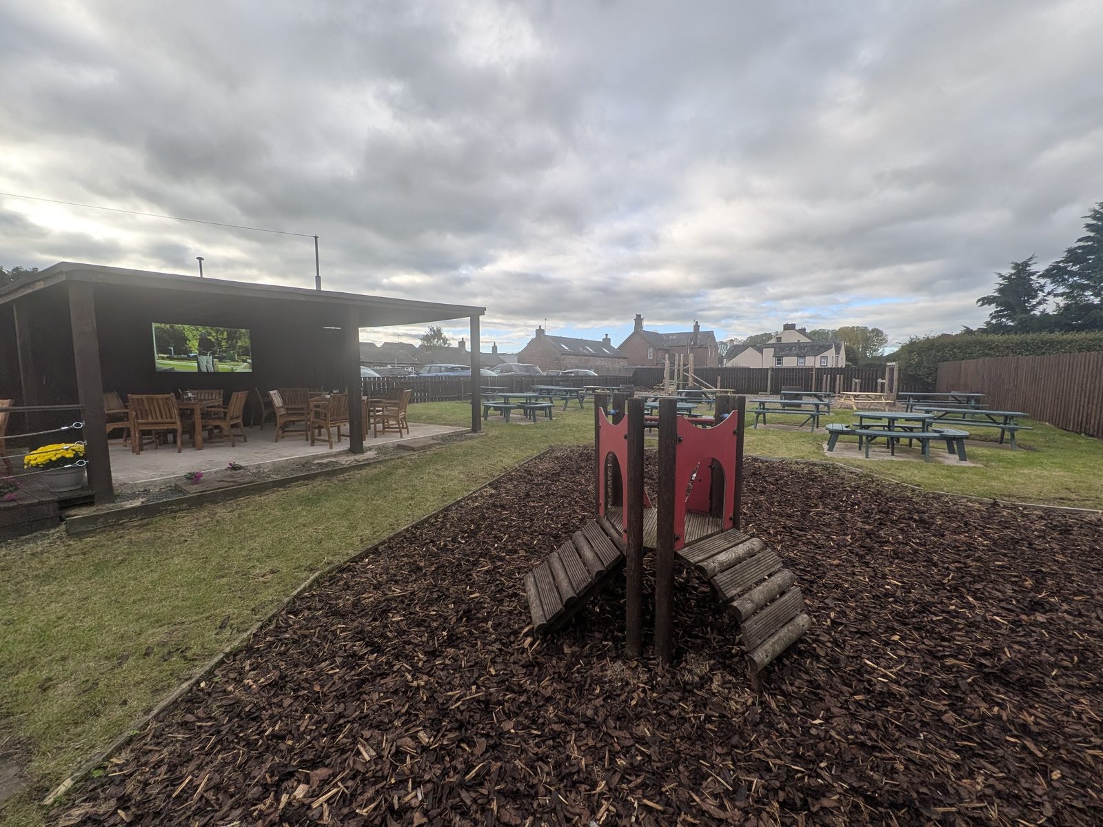 The children's play area at The Beehive, Eamont Bridge, with the covered seating and TV behind