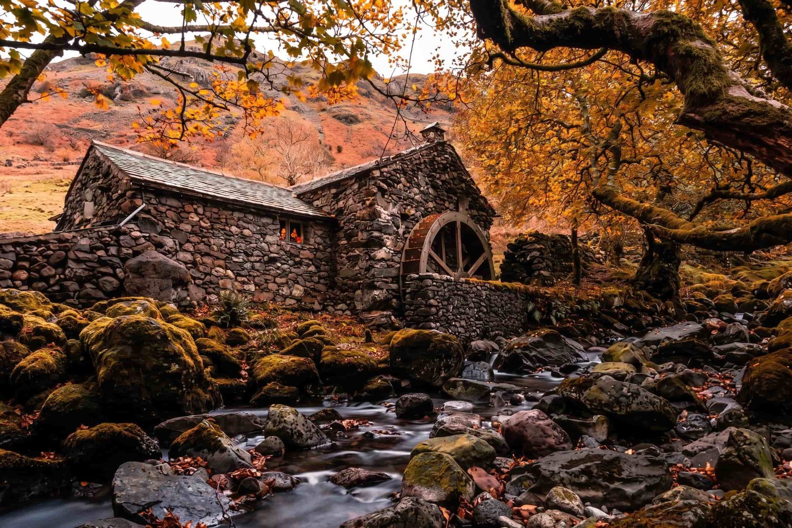 An old mill and waterwheel amid autumn woodland in Borrowdale, Lake District