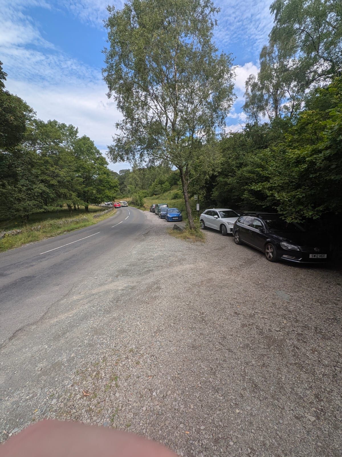 The roadside layby outside the Bowder Stone car park on the B5289, Borrowdale, with cars parked on the verge
