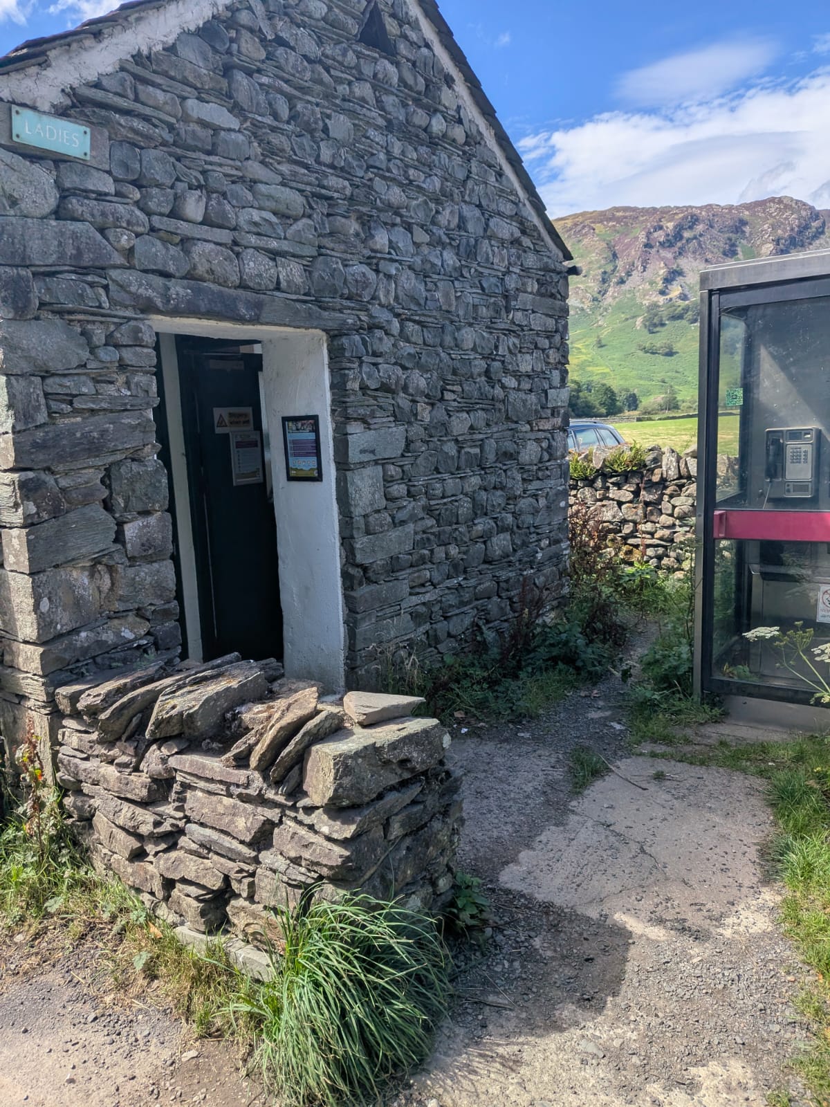 The stone public toilets block at Rosthwaite, Borrowdale, with a glass phone box beside it