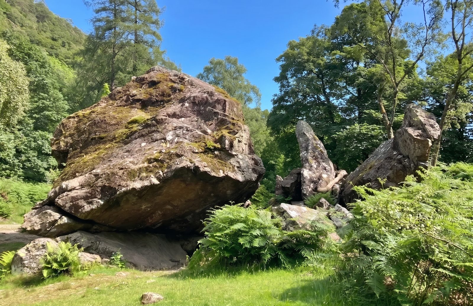 A visitor beside the Bowder Stone showing the scale of the boulder in the Jaws of Borrowdale, Lake District