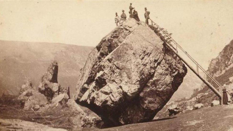 Victorian visitors standing on top of the Bowder Stone with the early ladder, 19th century, Borrowdale, Lake District