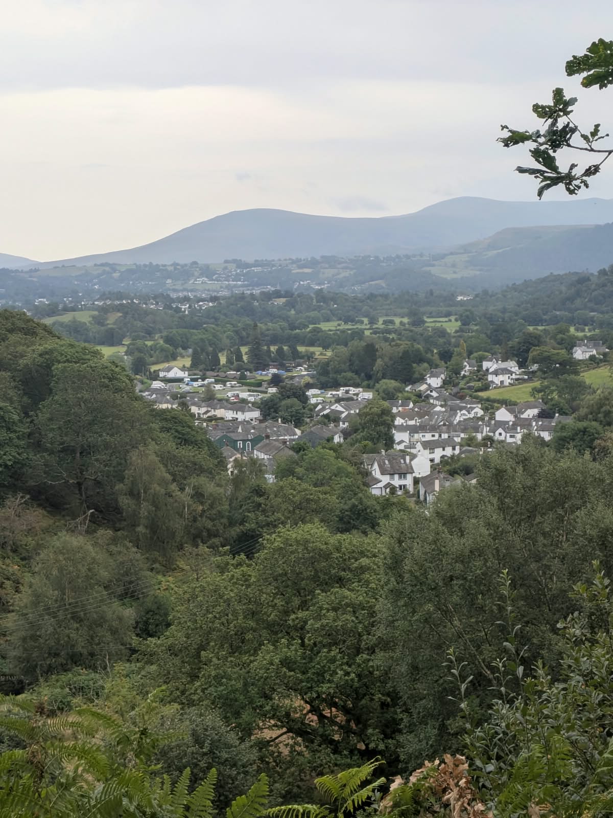 View over the rooftops of Braithwaite towards distant fells, with a campsite in the middle distance