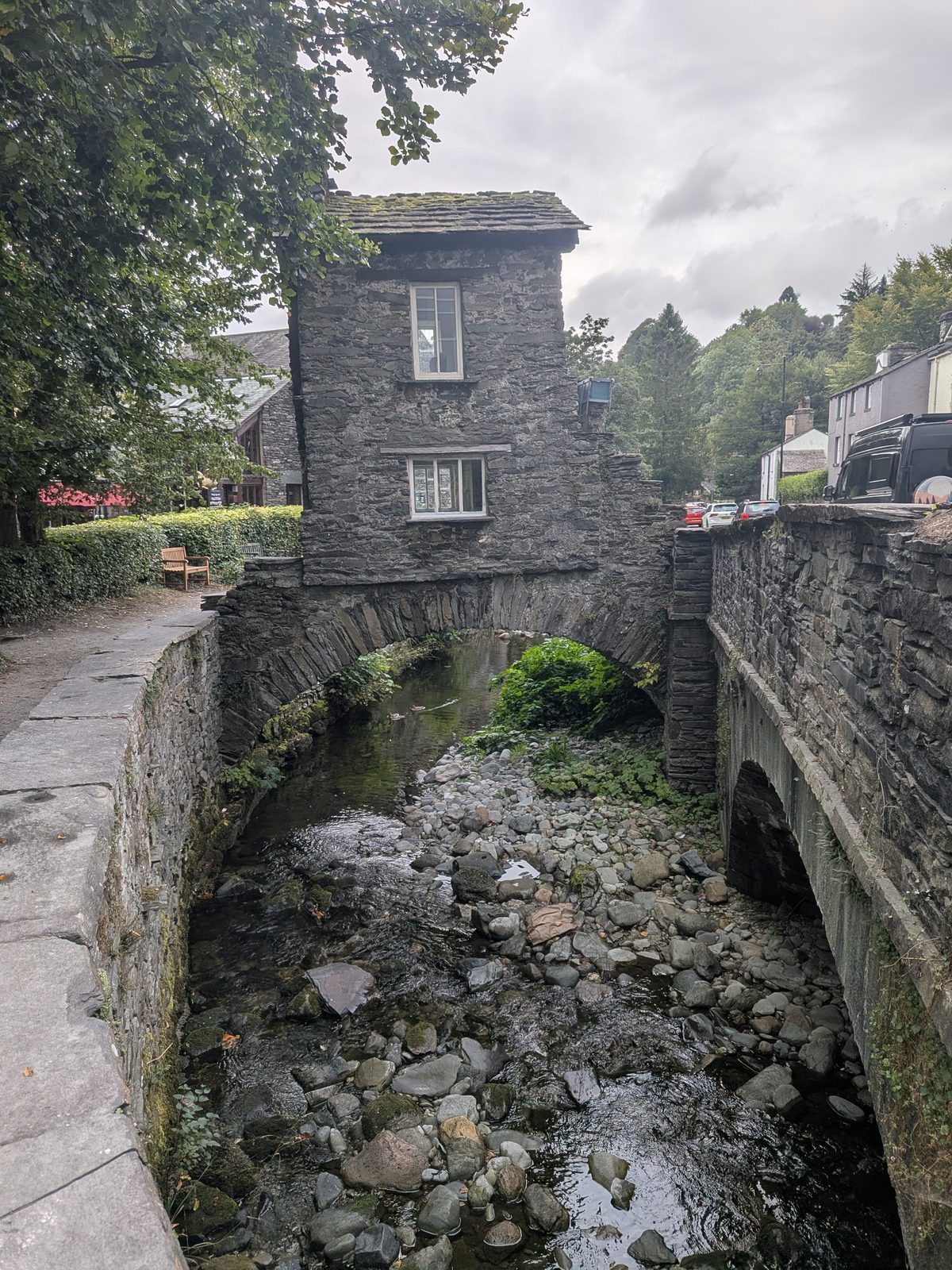 Bridge House, Ambleside: a small two-storey stone cottage built on an arched bridge over the rocky bed of Stock Ghyll