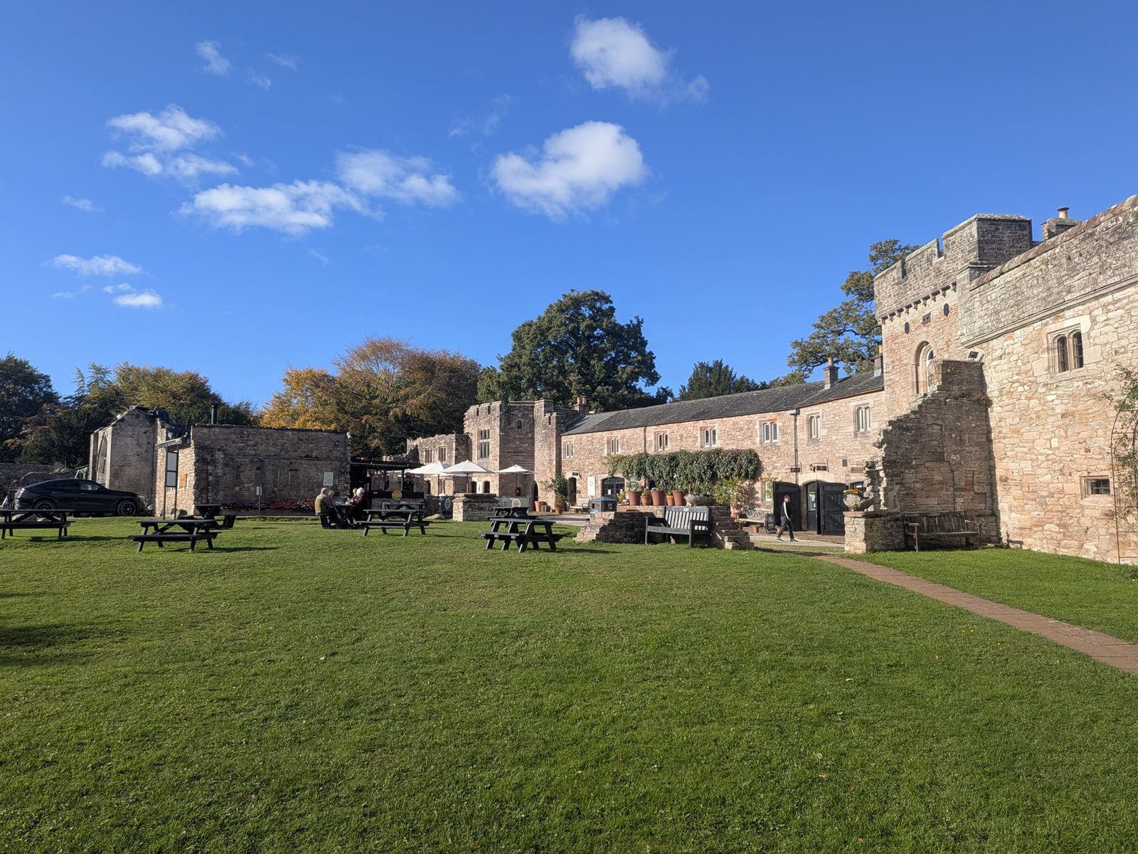 The lawn and sandstone ranges of the courtyard at Brougham Hall near Penrith, with picnic tables and a battlemented tower