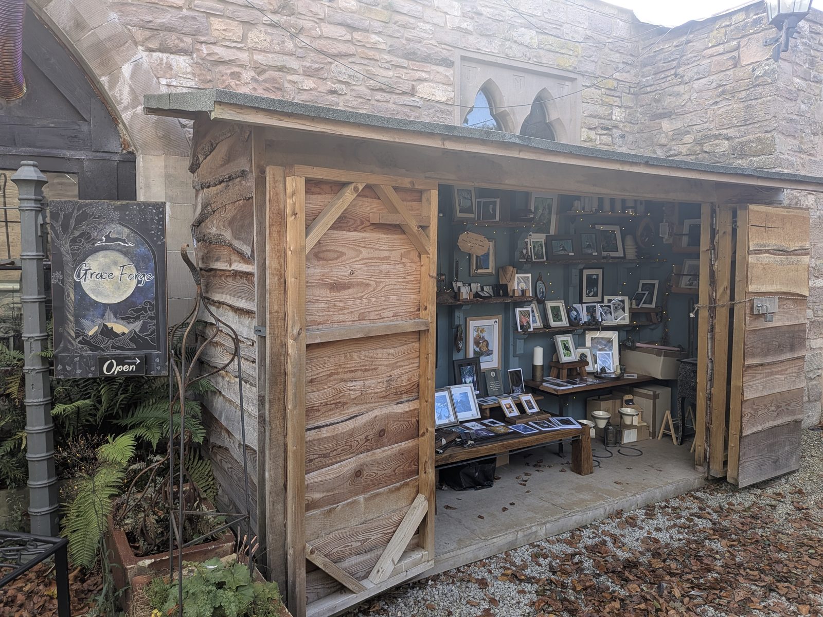 An open-fronted timber workshop at Grace Forge, Brougham Hall, with framed work on display inside
