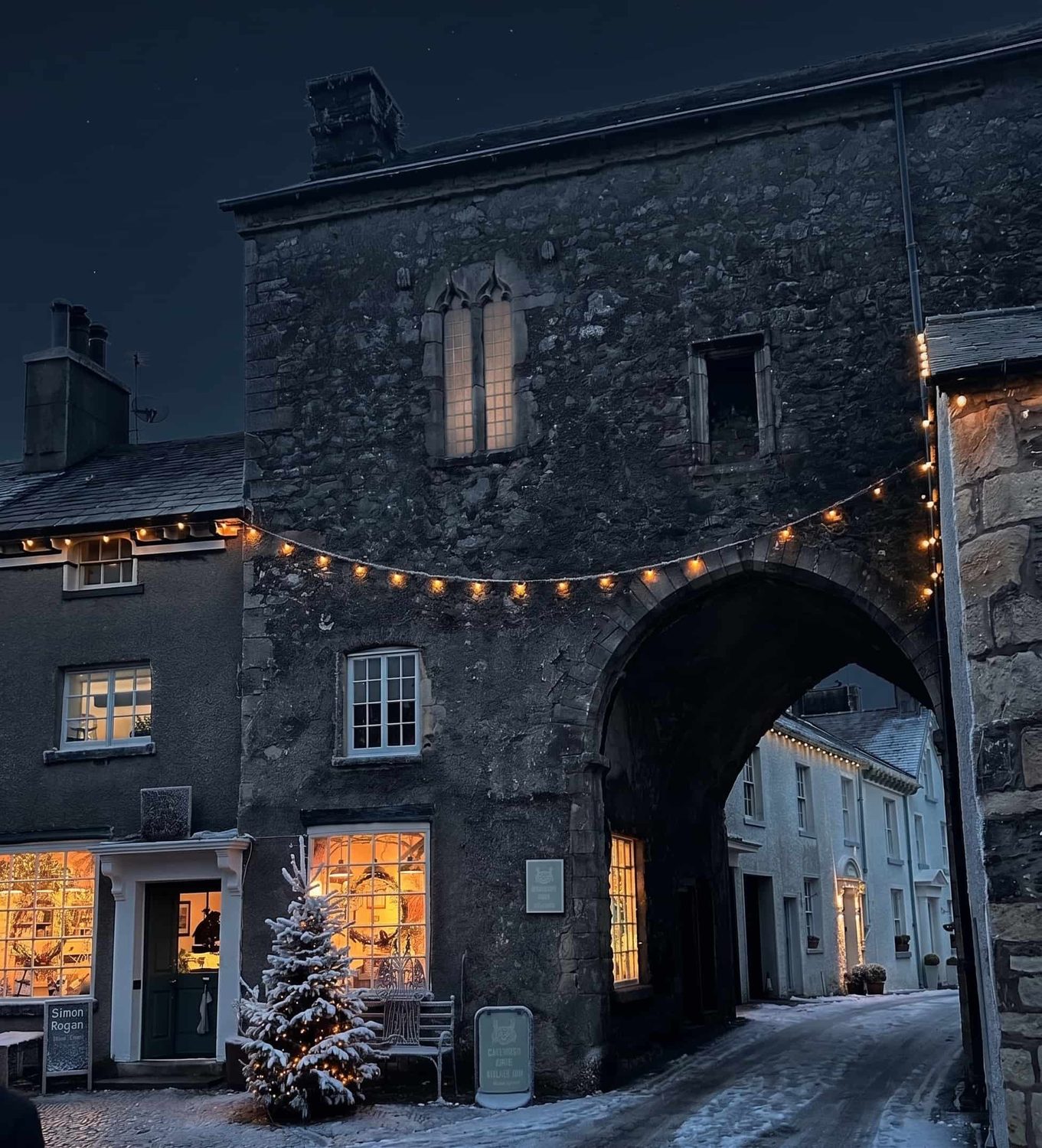 The medieval Cartmel Priory Gatehouse arch lit up at night in the village, Cumbria