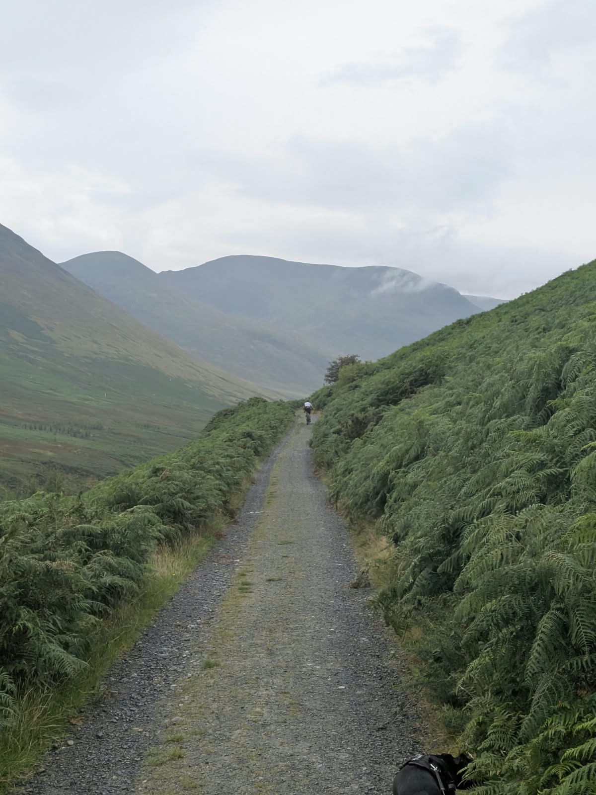Gravel track running between bracken into Coledale with a cyclist ahead in the distance