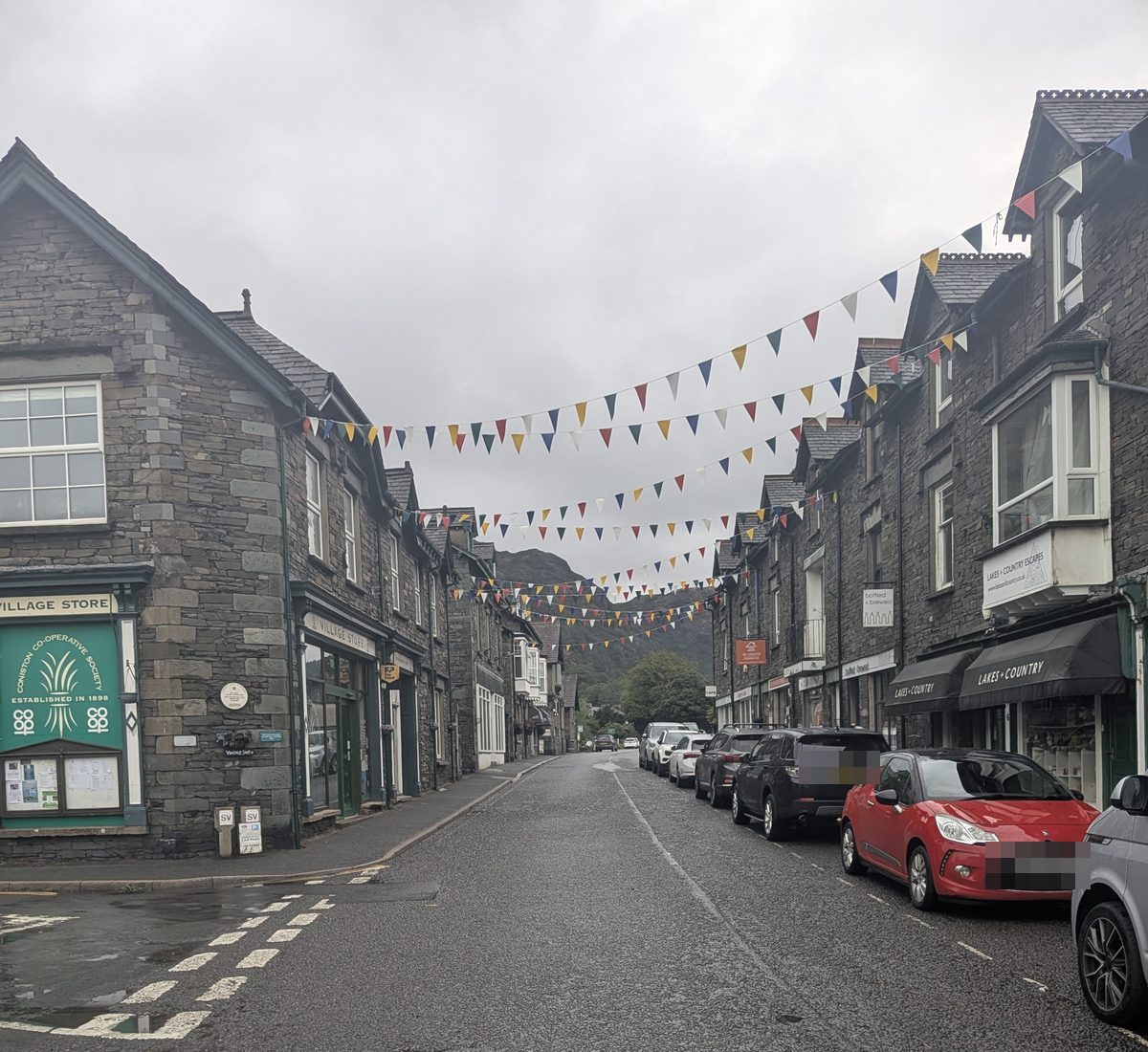 Bunting strung across the main street in Coniston, slate shopfronts on both sides and parked cars