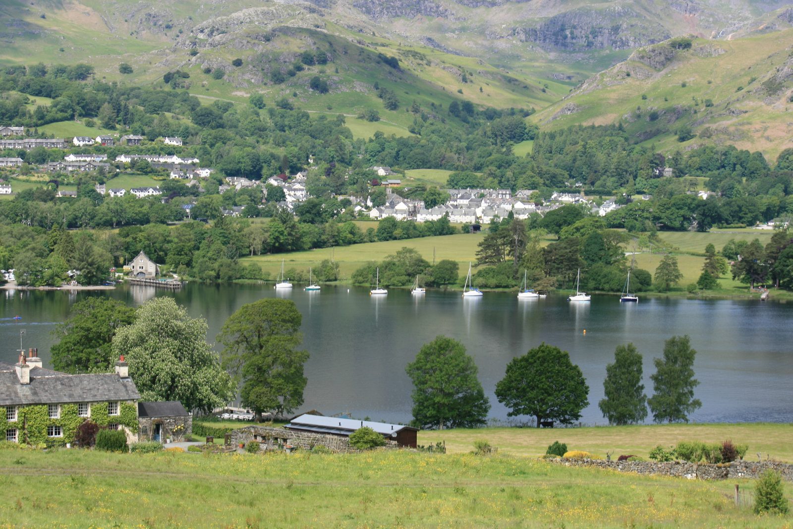 Coniston village on the far shore of Coniston Water, with the steep fellside of the Old Man range rising directly behind it