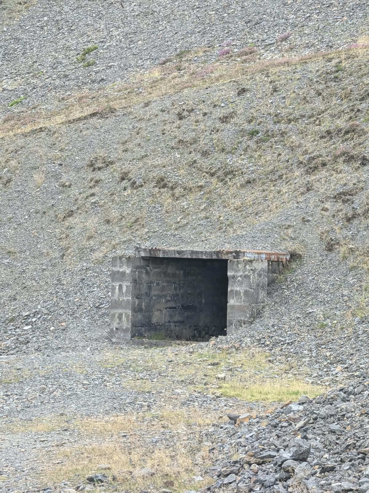 A blockwork mine entrance set into a slope of loose grey spoil