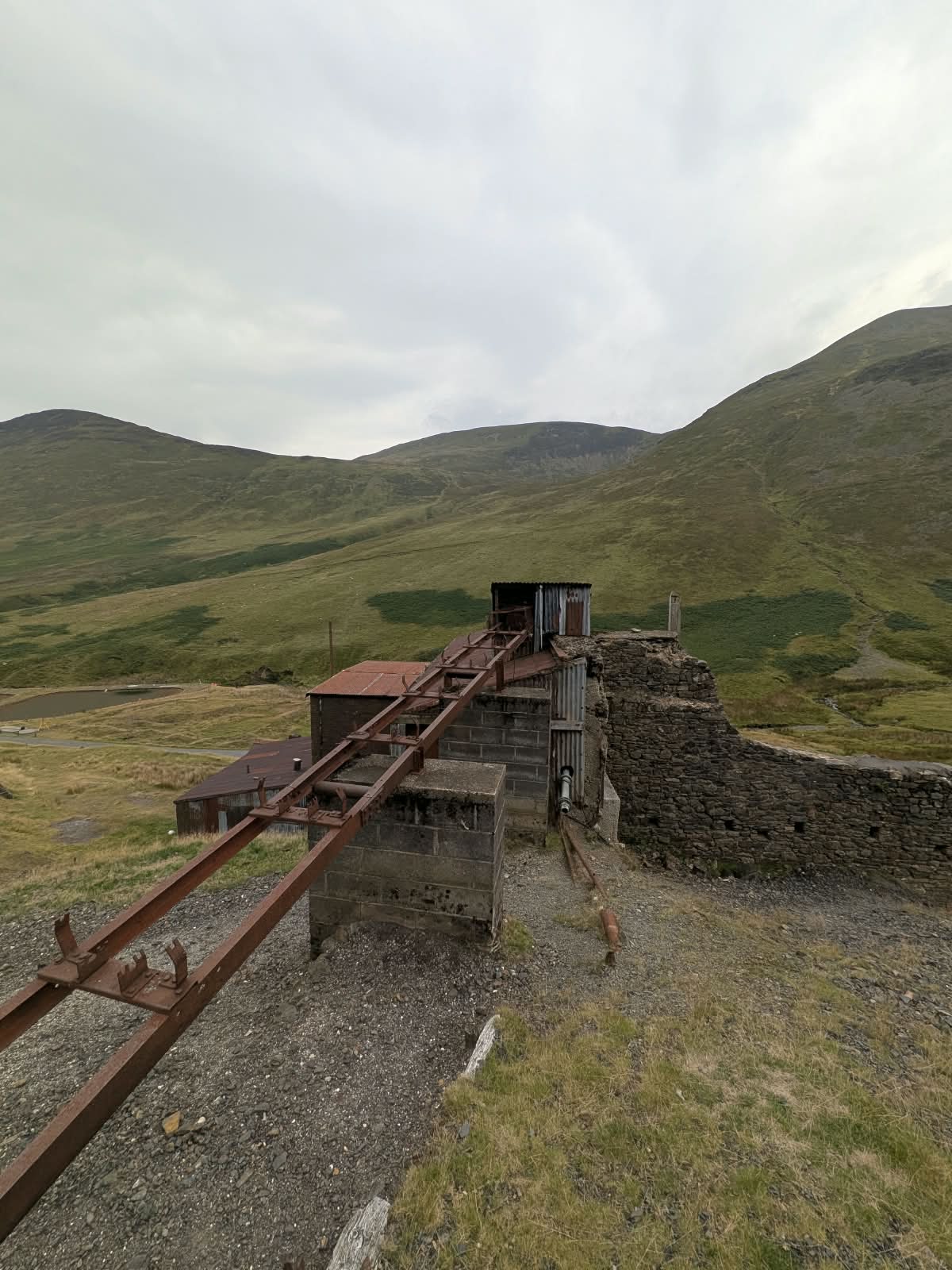 Rusted incline rails running down the hillside towards the buildings at Force Crag Mine