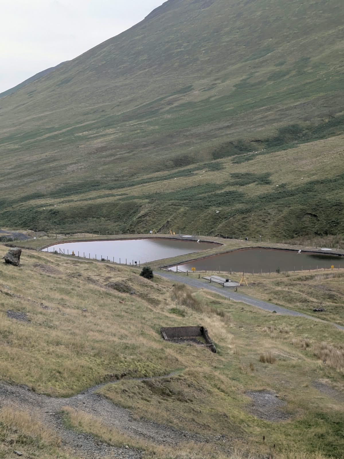 Two fenced water treatment ponds on the valley floor below the fellside at Force Crag