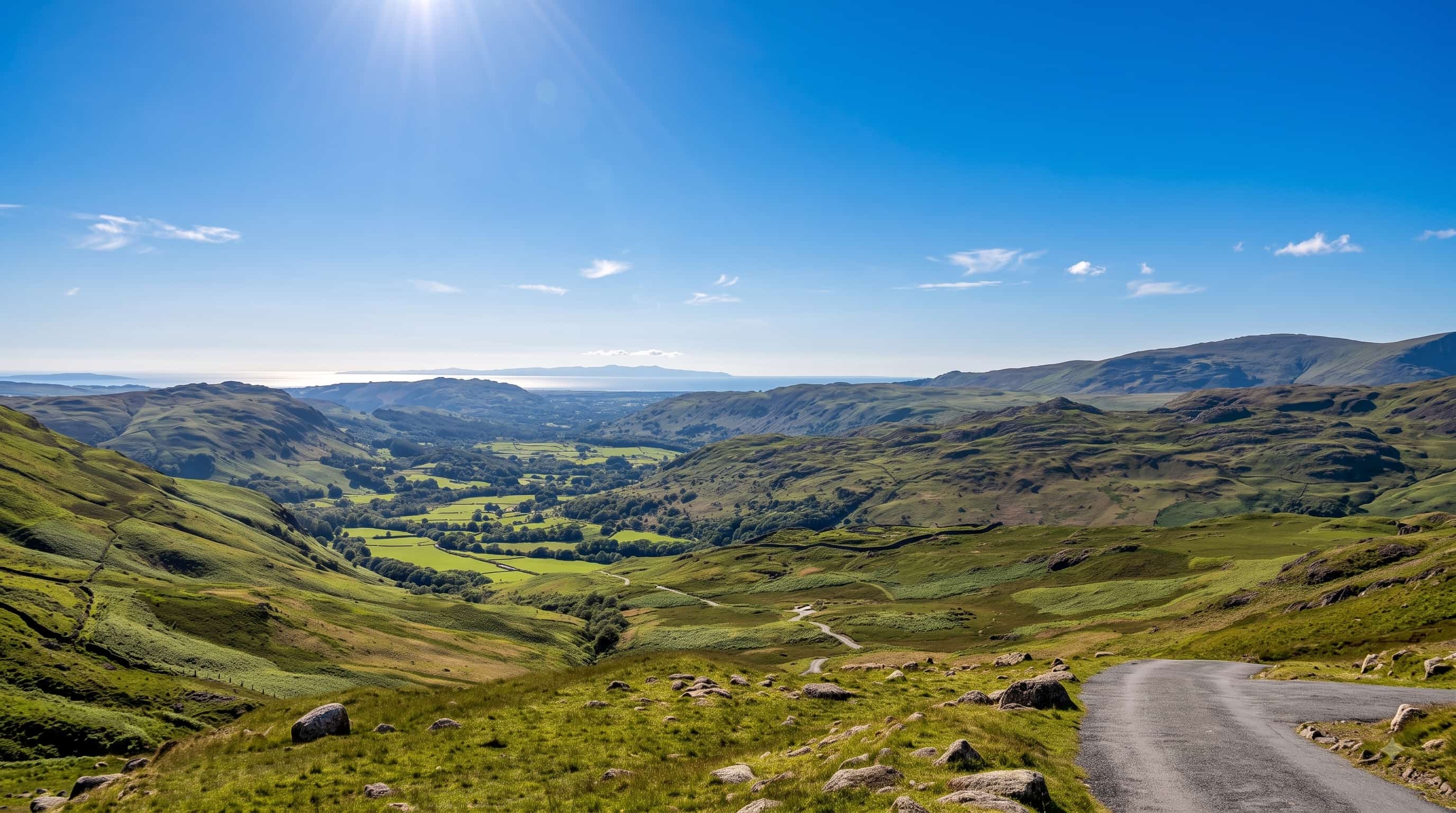 The view from the top of Hardknott Pass down Eskdale to the Cumbrian coast, Lake District, with the pass road winding away below