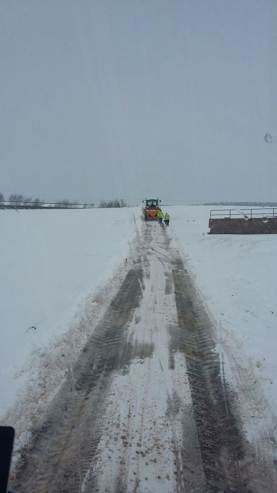 Snow on the A686 with a gritter tractor and crew ahead on the road