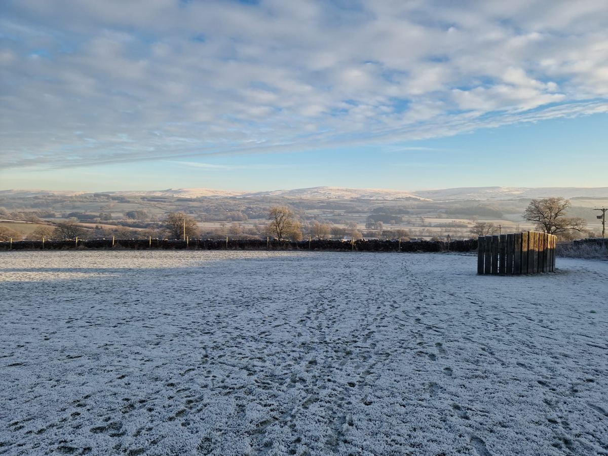 A frosted field at Lazonby with snow on the hills beyond under a sky of high cloud