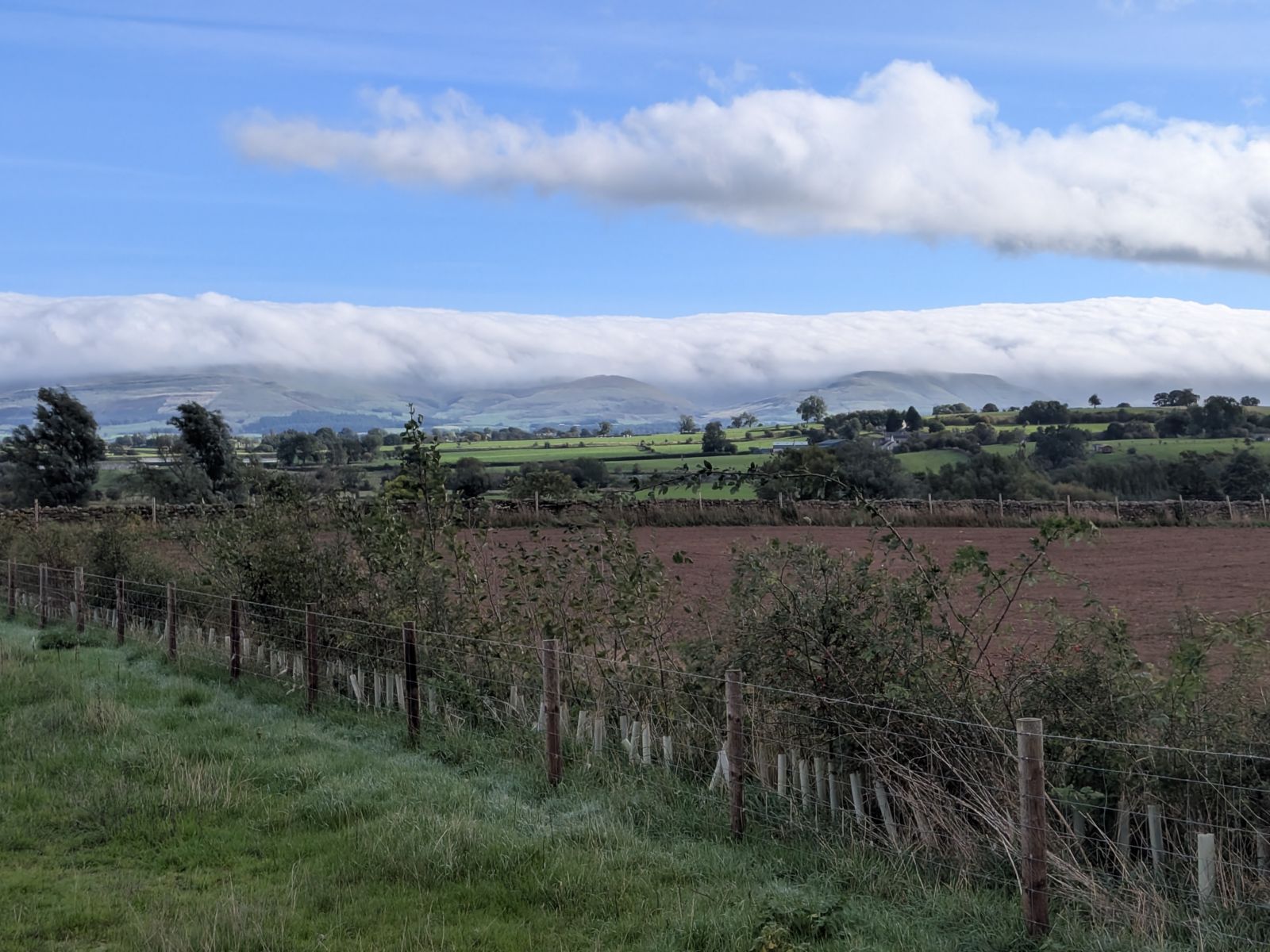 A cap of cloud lying on the ridge with a second, separate bar of cloud lying parallel above it