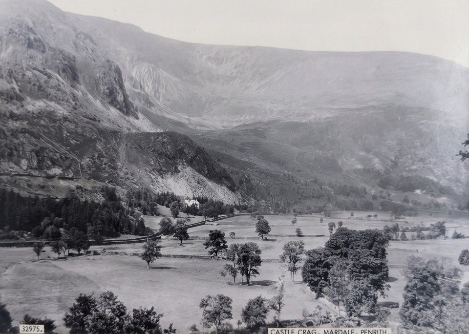 Old black-and-white photograph of Castle Crag, a rocky fellside rising above walled fields and trees on the floor of the Mardale valley
