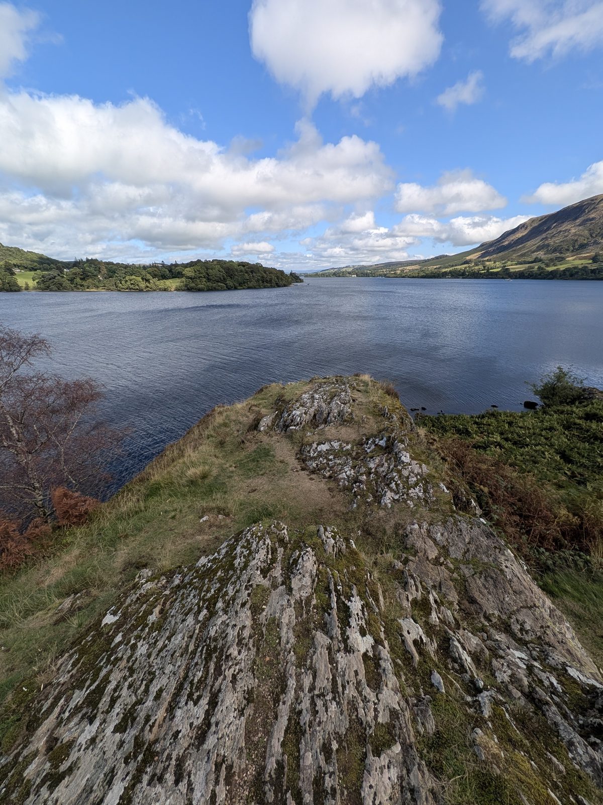 Kailpot Crag, a tilted rock promontory with grass on top, dropping into the water of Ullswater with the lake beyond