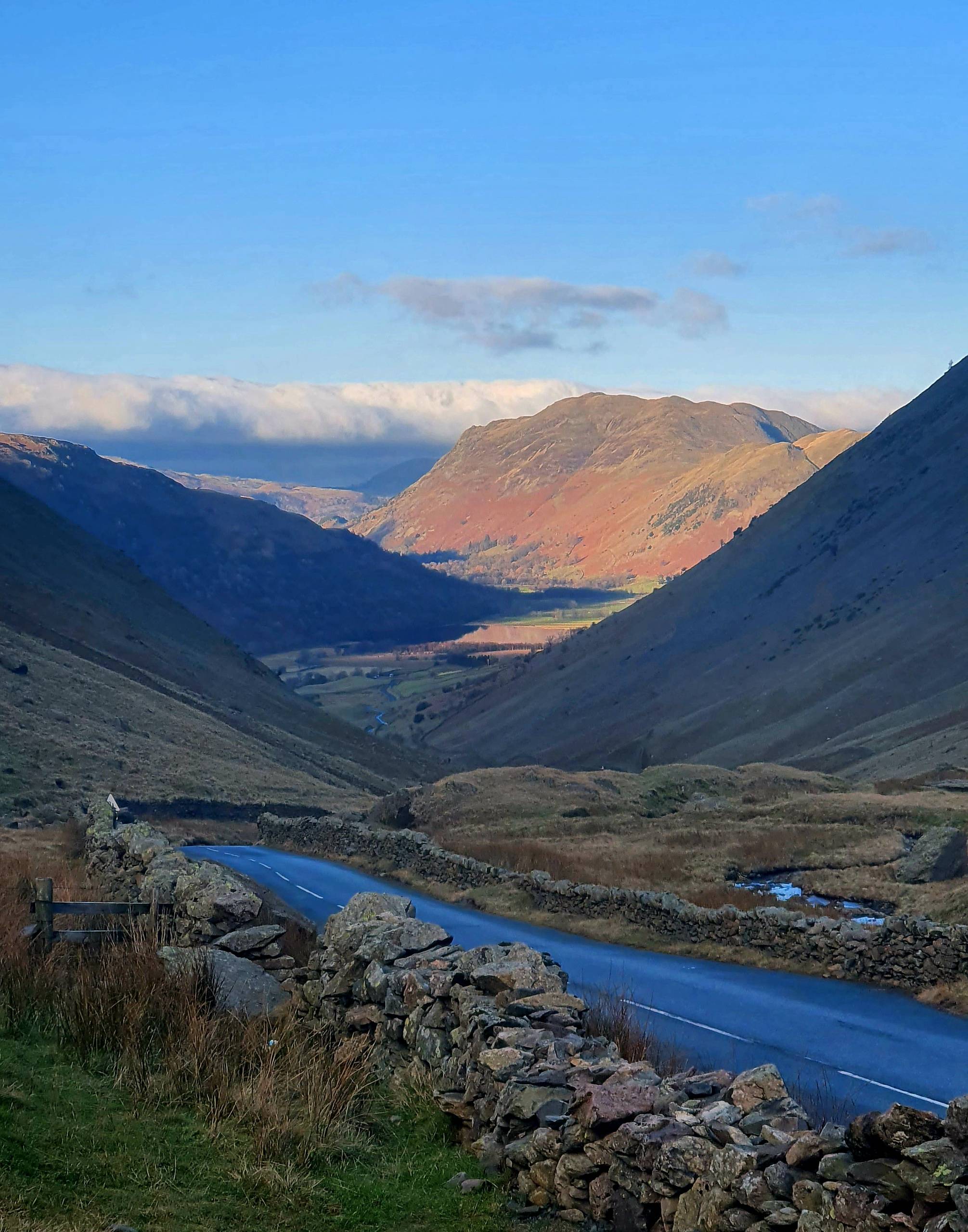 The A592 between dry stone walls dropping from Kirkstone Pass towards Brothers Water and Patterdale in winter light