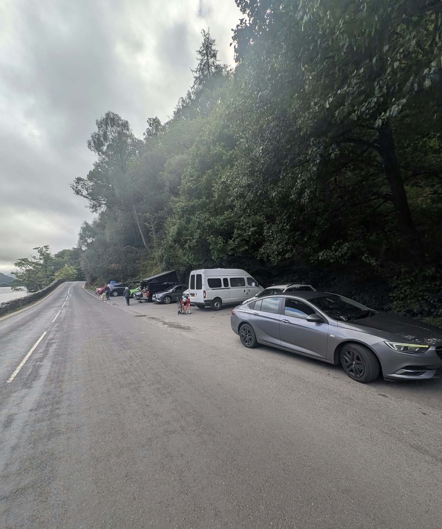 Cars parked in a small layby beside the A592 under trees near Glencoyne Bay