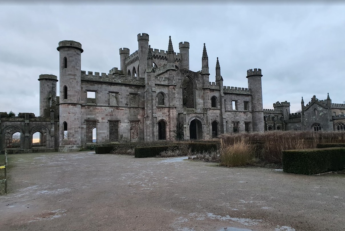 The garden front of Lowther Castle in midwinter — empty window openings with open sky behind them, frost on the ground