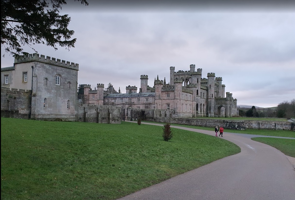 Lowther Castle seen from the drive on a midwinter afternoon, its battlements and gatehouse above open parkland near Penrith, Cumbria