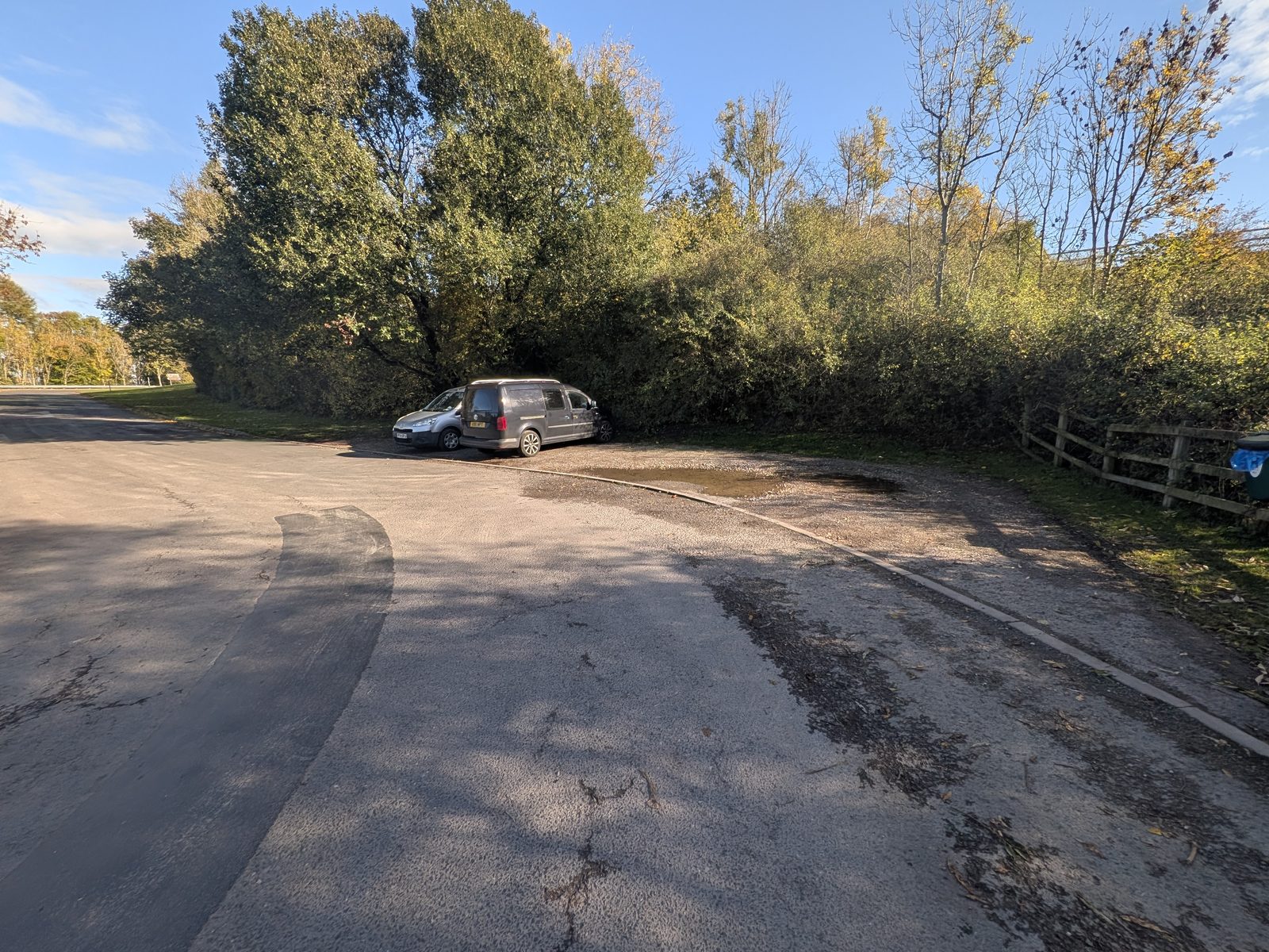 The small parking area for Mayburgh Henge at Eamont Bridge, with one car parked under the trees
