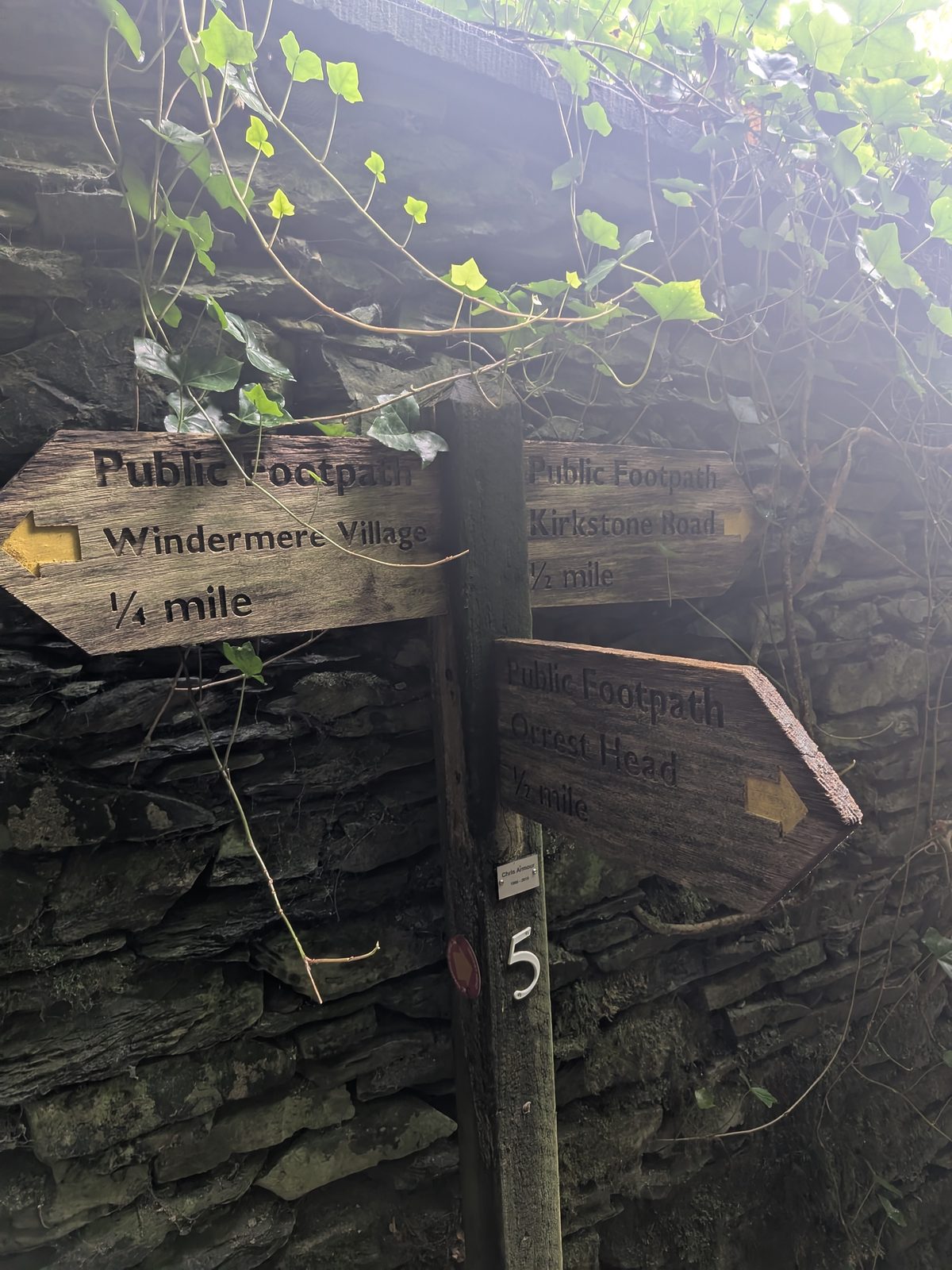 A wooden fingerpost pointing to Windermere Village, Kirkstone Road and Orrest Head