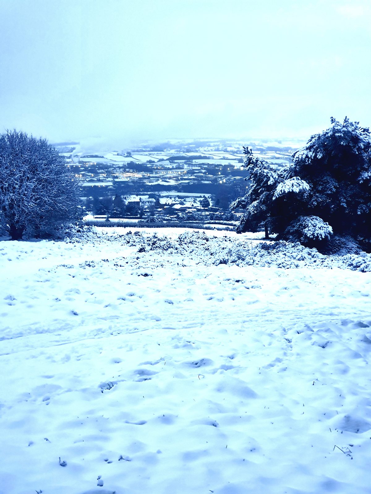 The snow-covered fairways of Penrith Golf Course with the town and the Eden Valley beyond