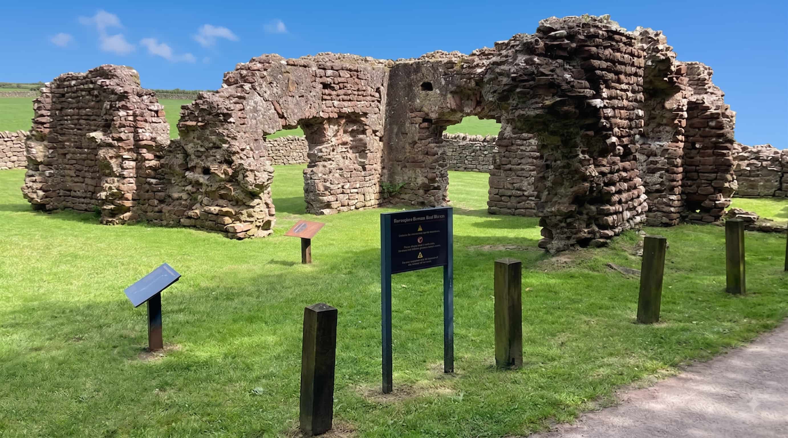 The standing red sandstone walls and arched doorways of the Roman bath house at Ravenglass, Lake District