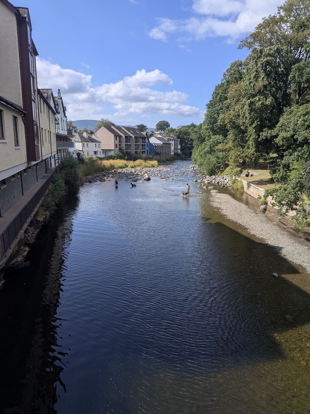Families paddling in the shallows of the River Greta in Keswick