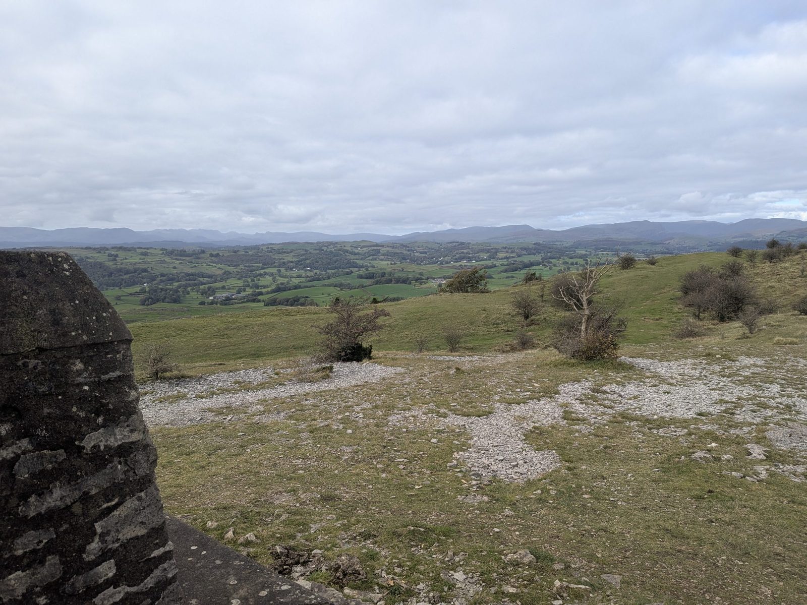 The view from beside the Mushroom's stone base on Scout Scar over grassland to the hills