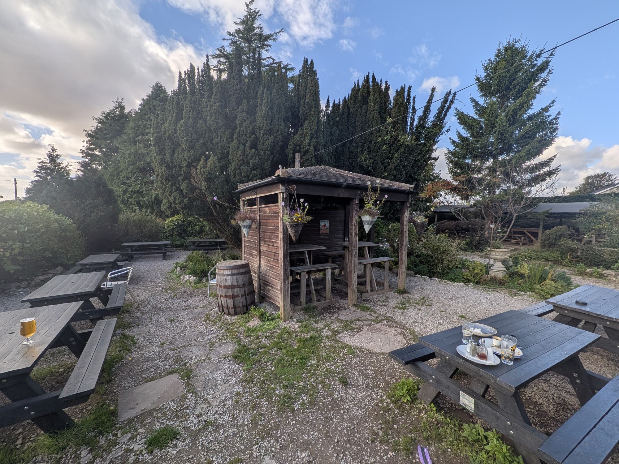 Picnic tables and a timber shelter in the gravel beer garden at The Silverdale Hotel