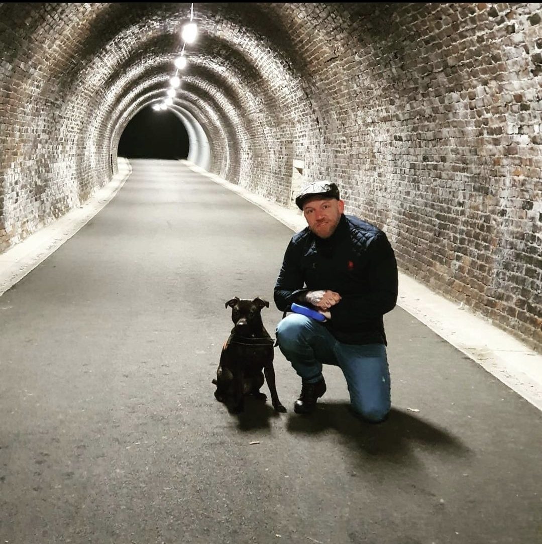 A walker and their dog stopped on the surfaced path of the Keswick to Threlkeld railway trail
