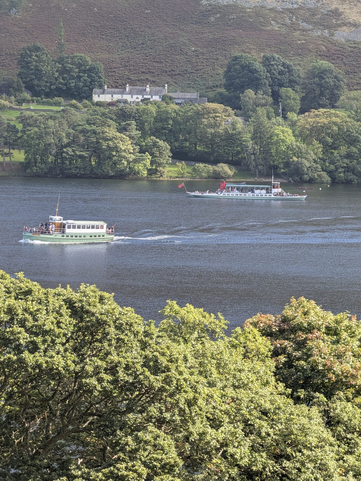 Two Ullswater Steamers passing each other on the lake, a house and wooded shore behind them
