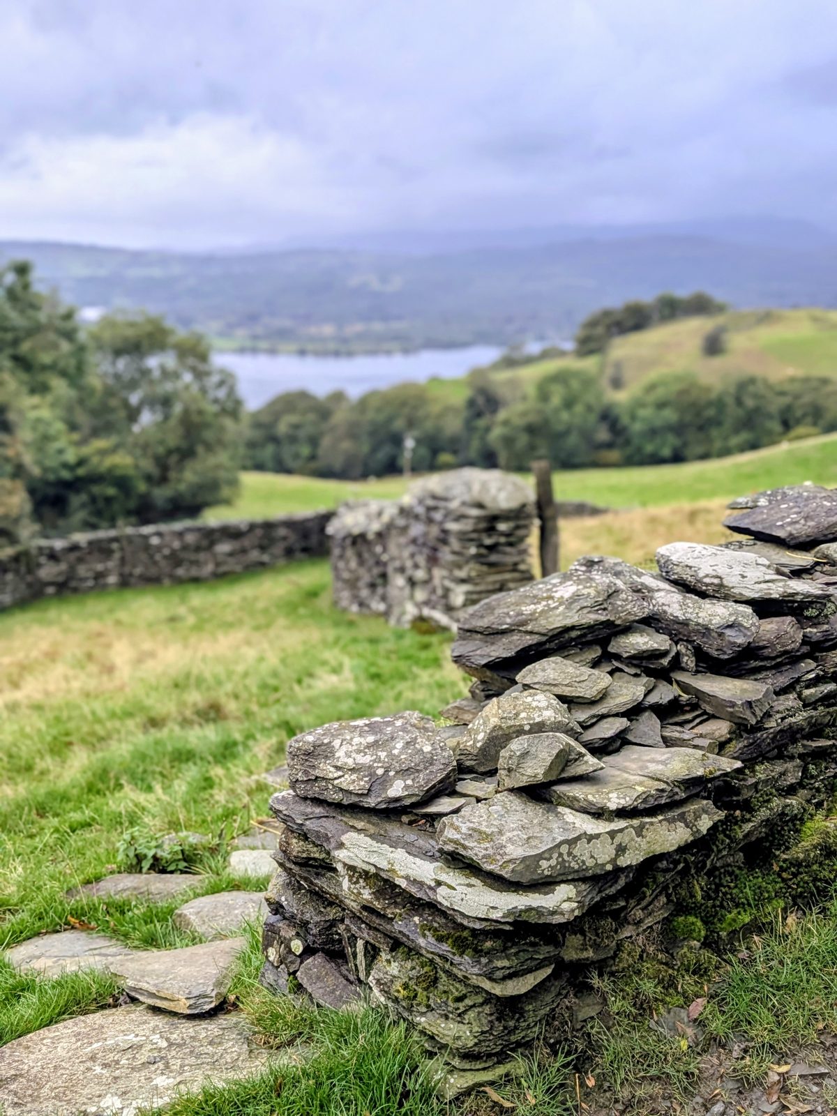 A stack of slate at the end of a dry-stone wall, with a lake beyond